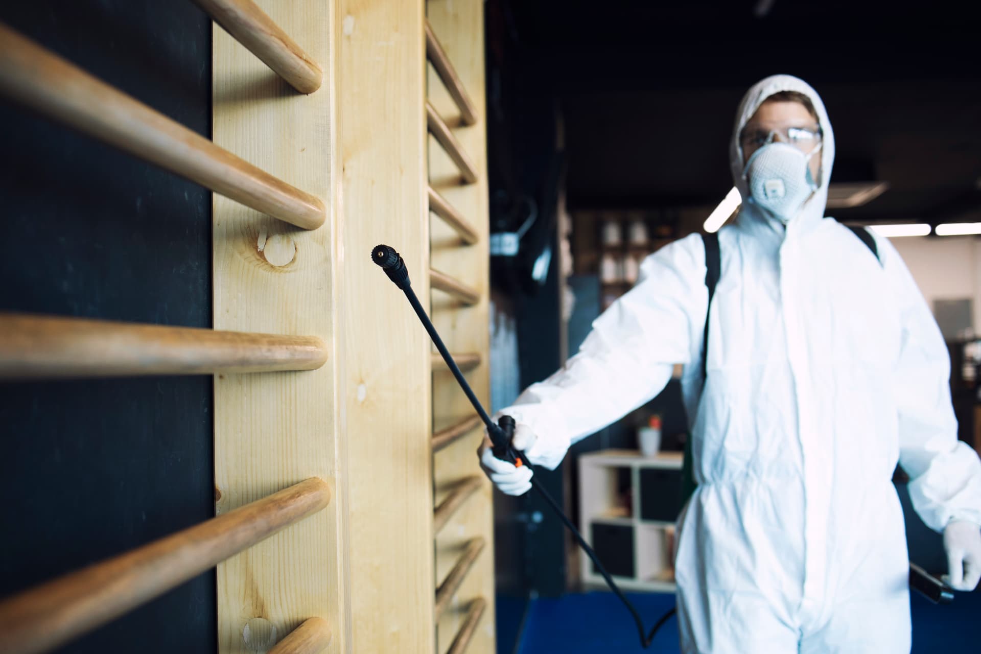 Technicien en tenue de protection réalisant une désinfection de locaux